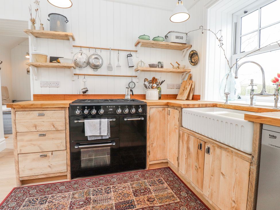 A kitchen with wooden cabinets and shelves at 4 bed in Anglesey