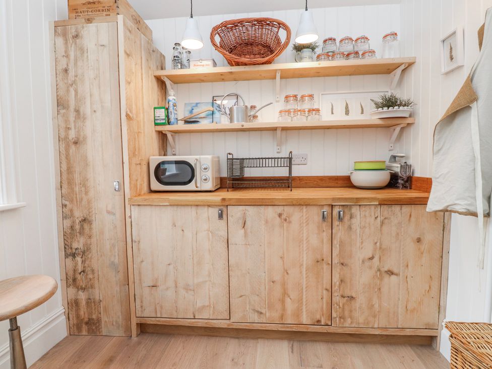 A kitchen with wooden cabinets and a microwave at 4 bed in Anglesey