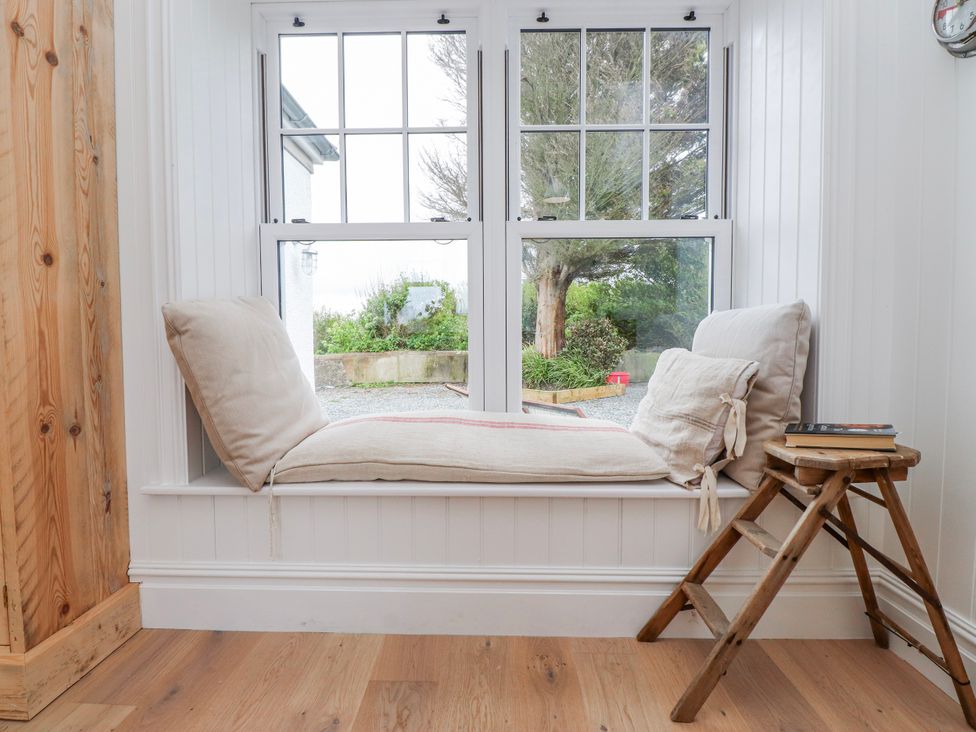 A window seat with cushions and a small stool at 4 bed in Anglesey