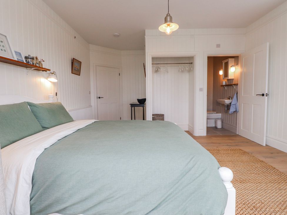 A bedroom with a bed and bathroom access at 4 bed in Anglesey