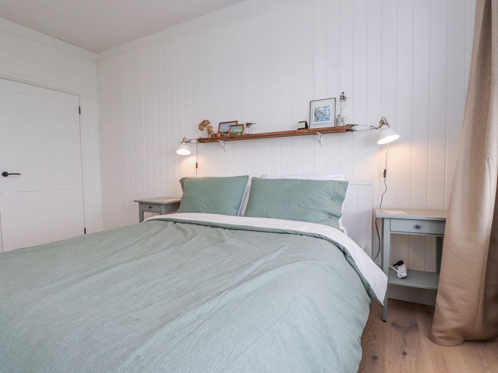 A bedroom with a bed and nightstands at 4 bed in Anglesey