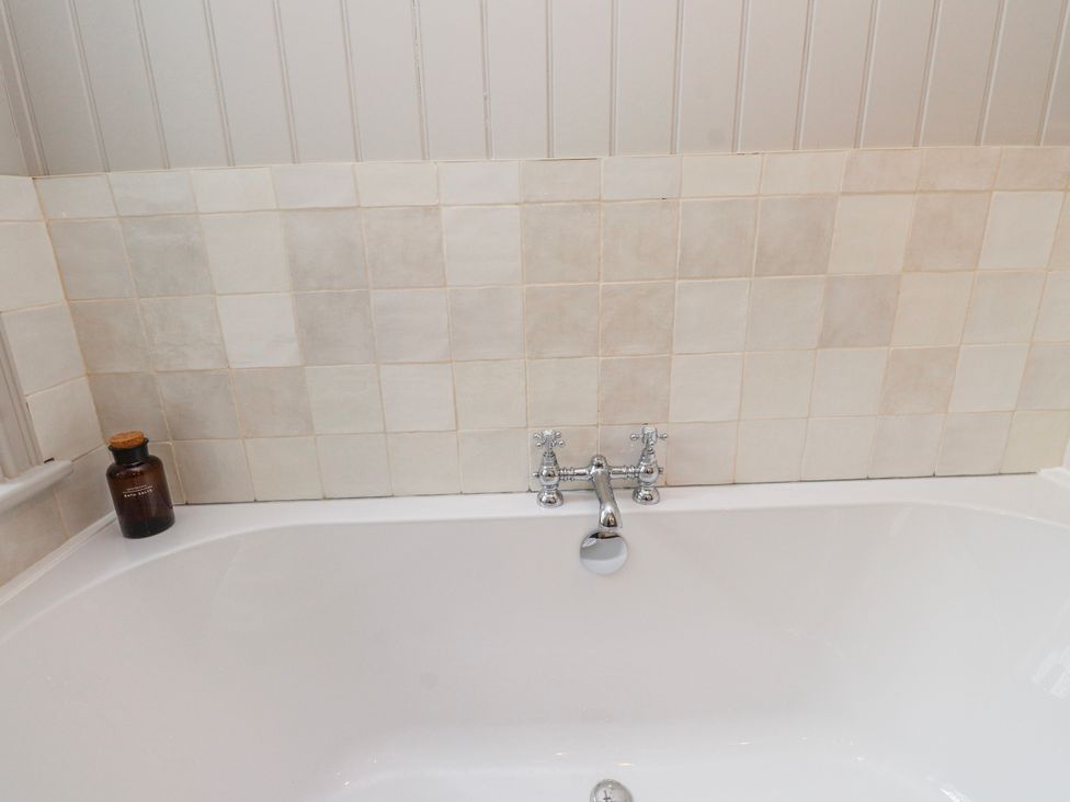 A bathtub with a faucet and bottles at 4 bed in Anglesey