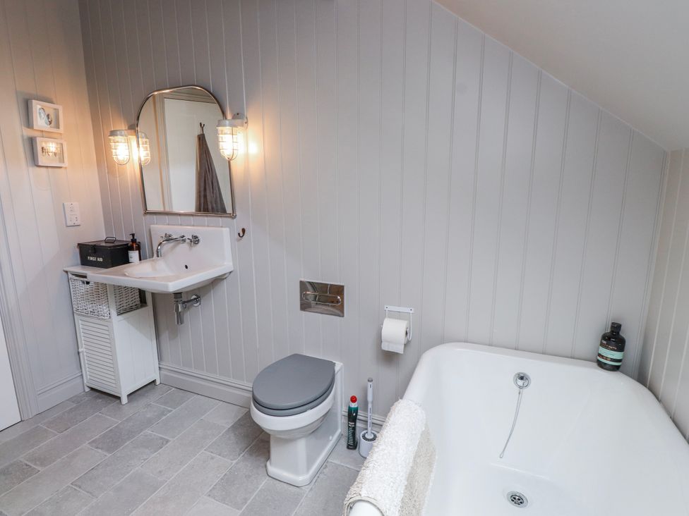 A bathroom with a sink, mirror, toilet, and bathtub at 4 bed in Anglesey