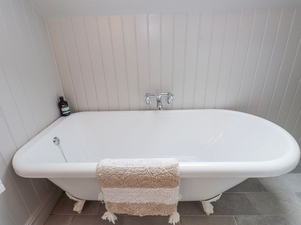 A bathtub with a towel and a bottle in a bathroom at 4 bed in Anglesey
