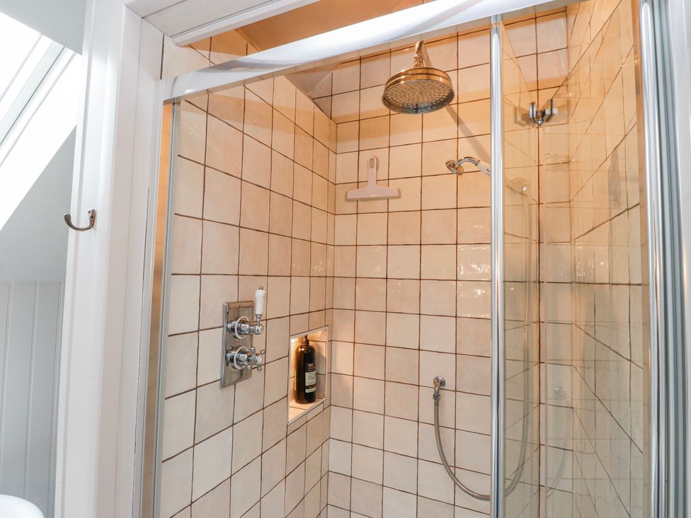 A shower with tiled walls and controls at 4 bed in Anglesey