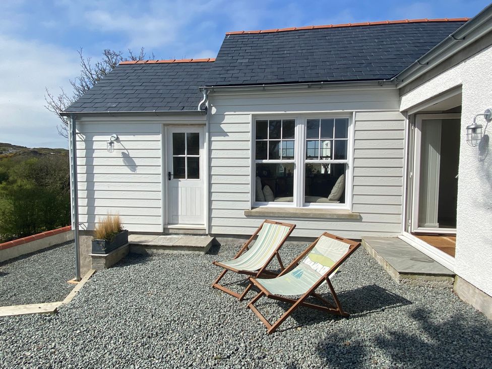 A house with two deck chairs and a gravel area at Arfryn 