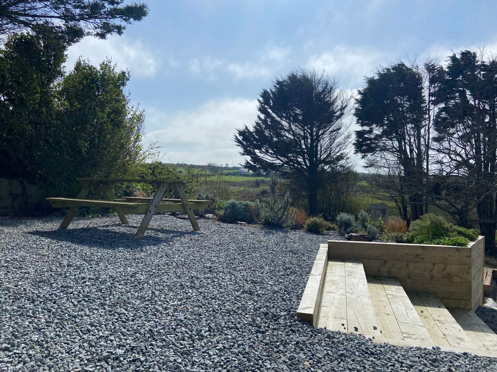 A garden with picnic table and gravel at Arfryn