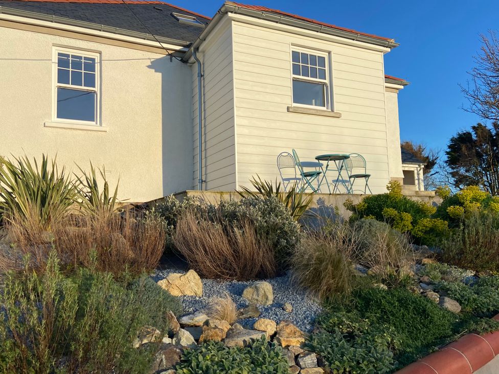A house with a table and chairs on a patio surrounded by plants at Arfryn