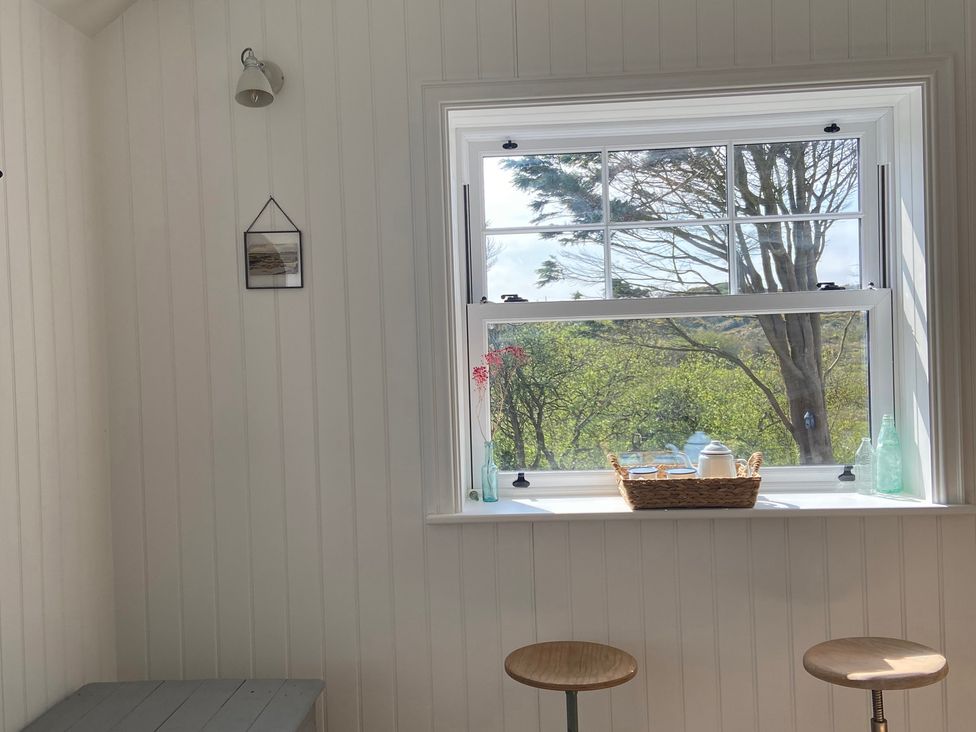 A kitchen with a window and stools at Arfryn in Bull Bay
