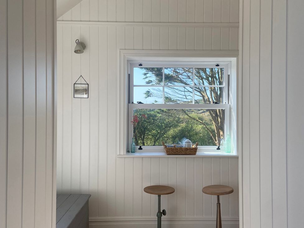A small room with a window and stools at Arfryn in Bull Bay