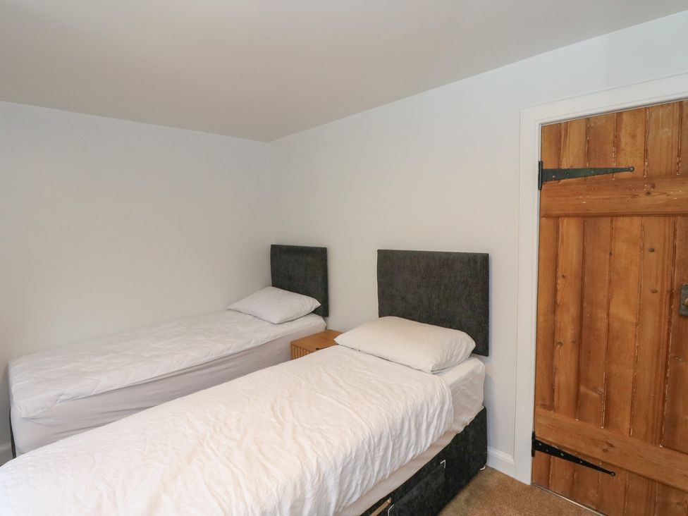 A bedroom with two beds and a wooden door at 8 Douglas Place