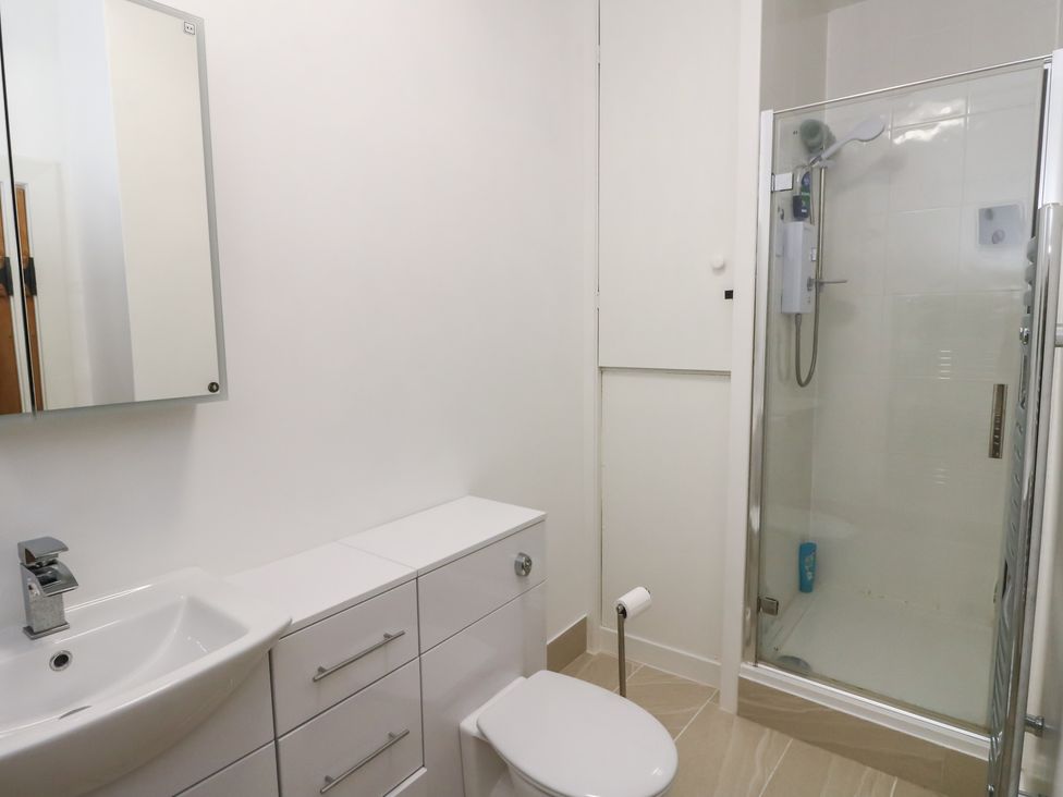 A bathroom with a shower, toilet, sink, and mirror at 8 Douglas Place