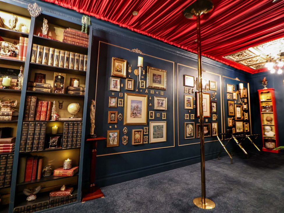 A library with bookshelves and framed pictures at The Hollow in Holywell