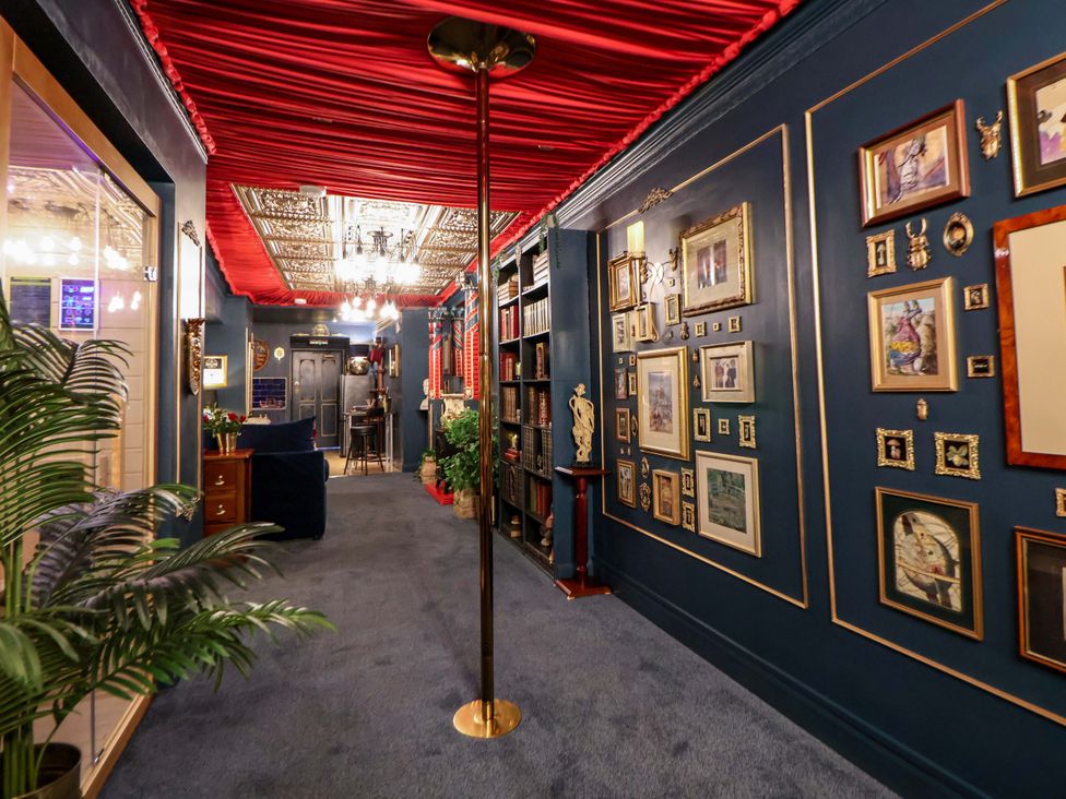 A hallway with decorative frames and a bookshelf at The Hollow in Holywell