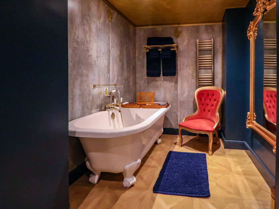 A bathroom with a bathtub and a chair at The Hollow in Holywell