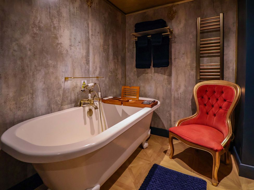 A bathroom with a bathtub and a red chair at The Hollow in Holywell
