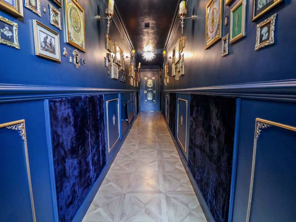 A hallway with framed art and a door at The Hollow in Holywell
