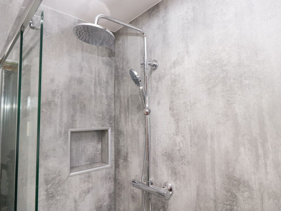 A shower with a glass door and a chrome showerhead at Rocklands in Shap