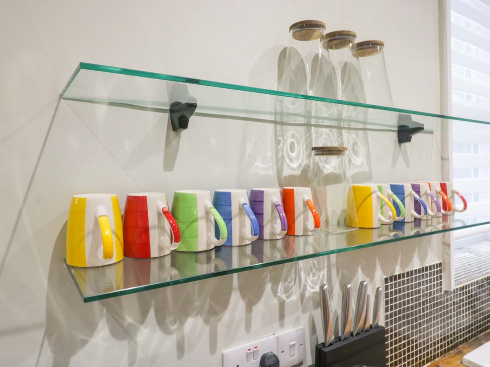 A shelf with colorful mugs and glasses in a kitchen at Rocklands in Shap