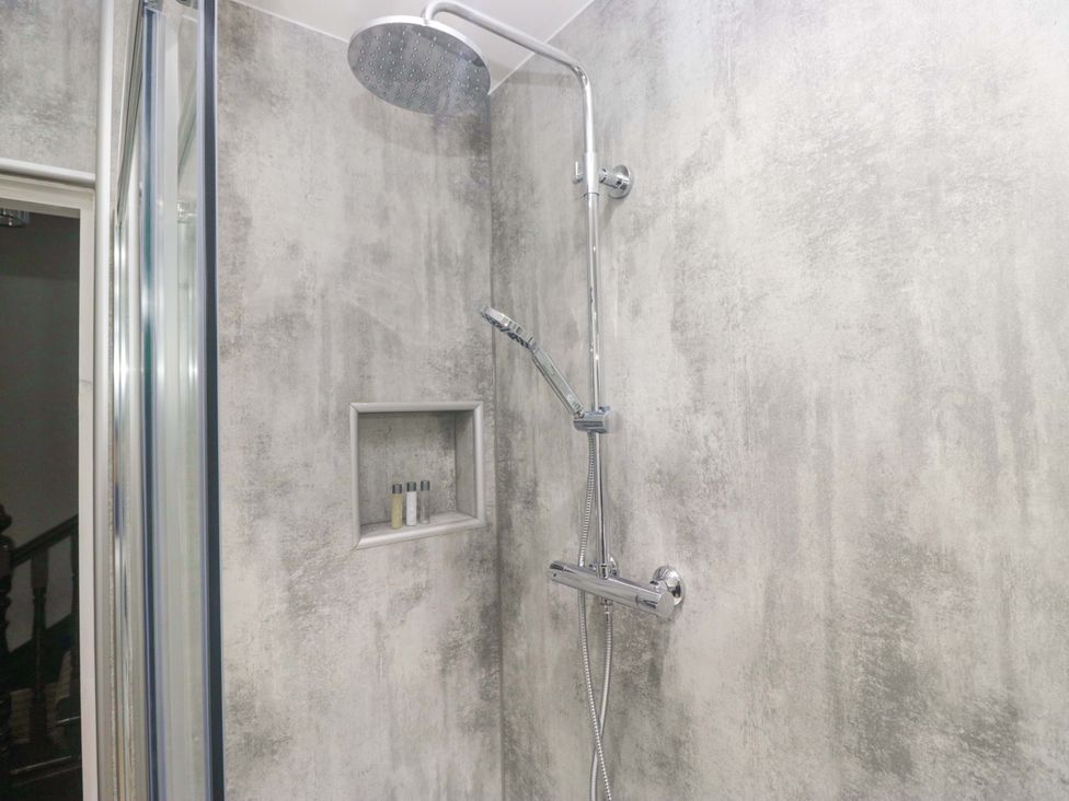 A shower with a chrome shower head and niche with bottles at Rocklands in Shap