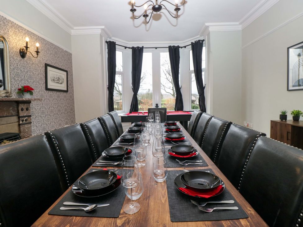 A dining room with a long table set for a meal at Rocklands in Shap