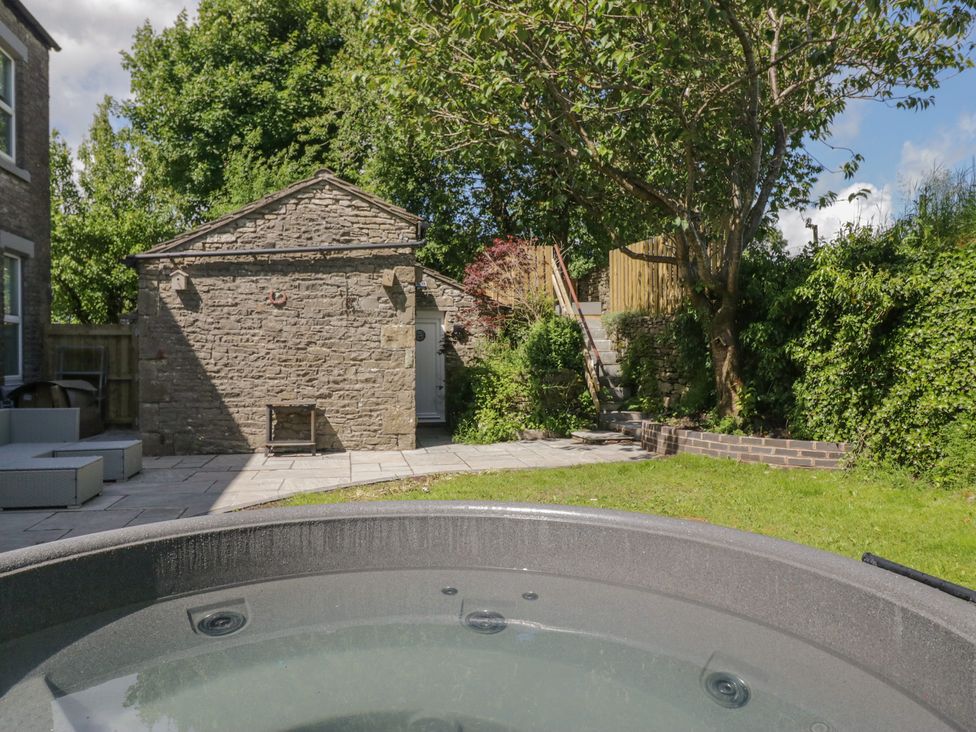 A garden with a hot tub and stone building at Rocklands in Shap