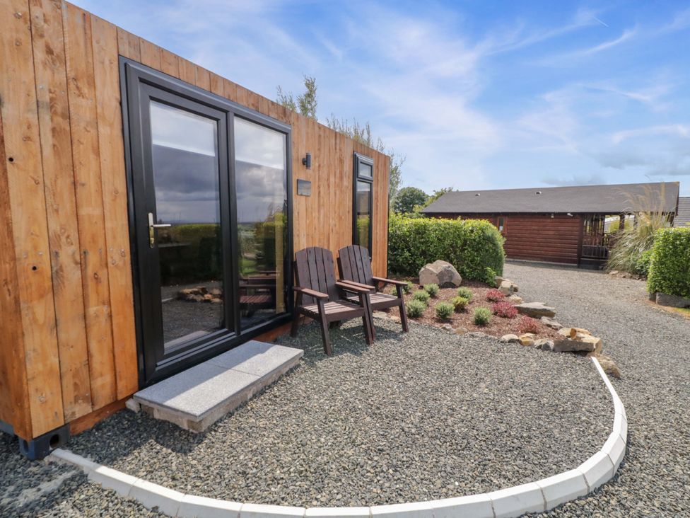 A wooden cabin with chairs outside in an outdoor area at Alken The Hare in Bushmills
