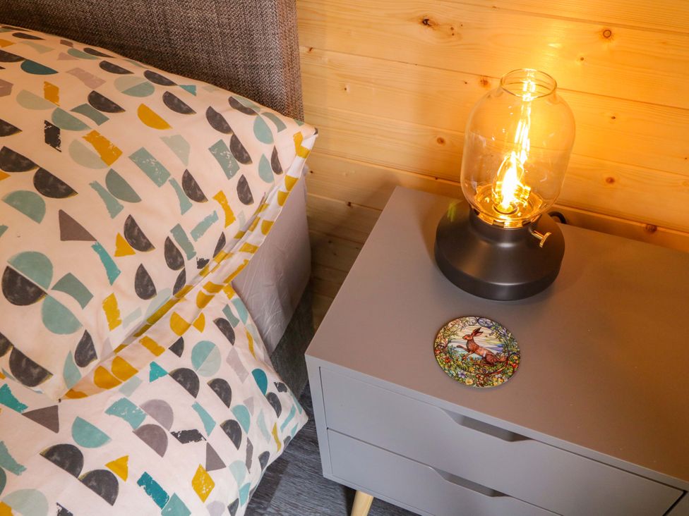 A bedside table with a lamp and pillow at Alken The Hare in Bushmills