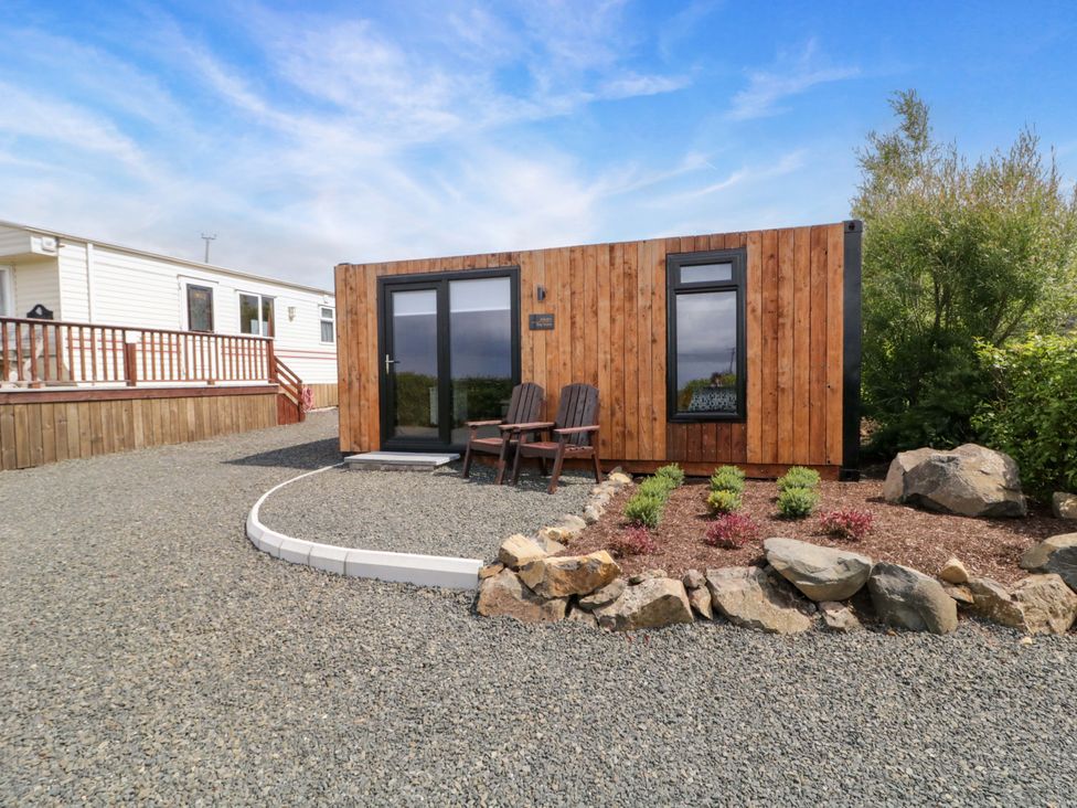 A wooden cabin with chairs and gravel landscaping at Alken The Hare in Bushmills