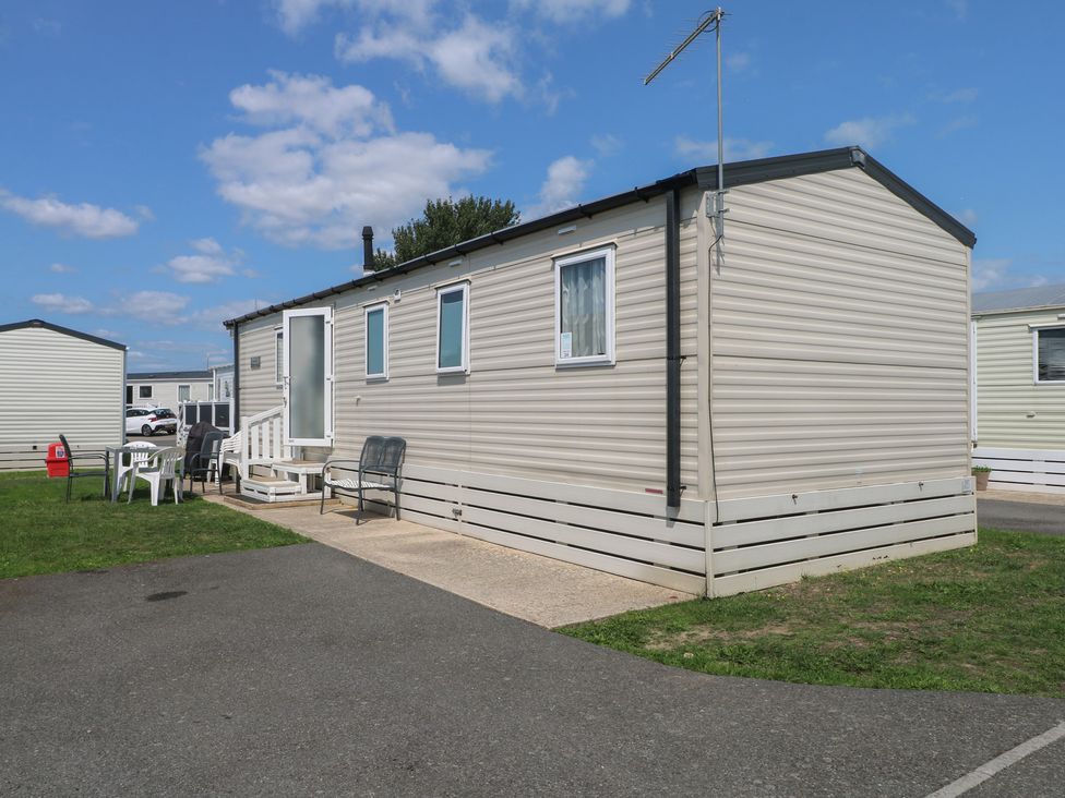 A mobile home with chairs on the patio at Tower View Number 34 Pevensey