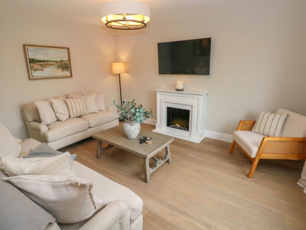 A living room with a sofa, coffee table, and television at Hafan Y Gof Newcastle Emlyn