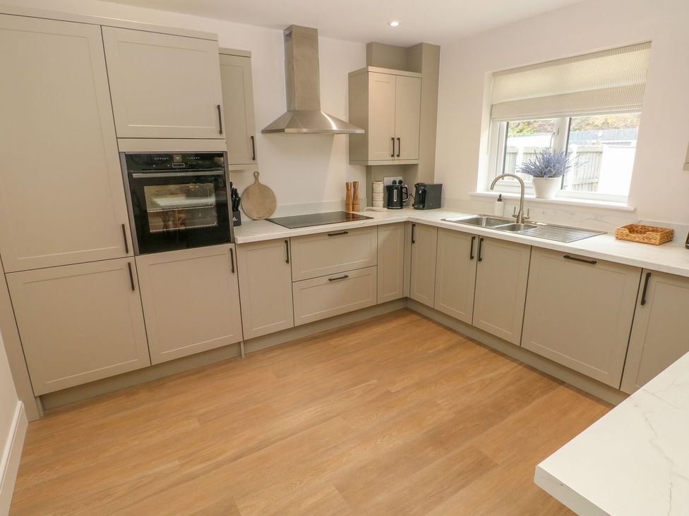 A kitchen with cabinets, sink, oven and coffee machine at Hafan Y Gof Newcastle Emlyn