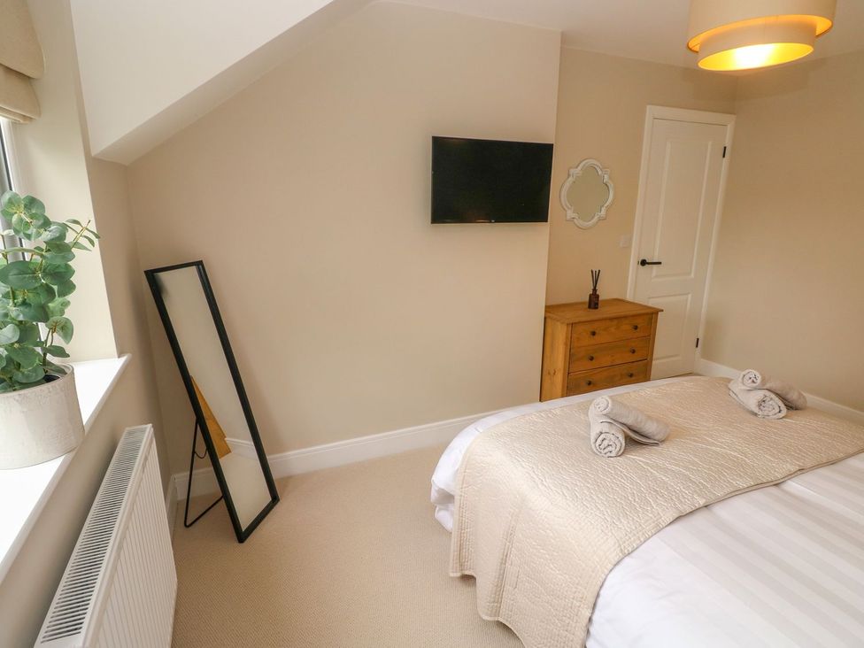 A bedroom with bed, television and mirror at Hafan Y Gof in Newcastle Emlyn