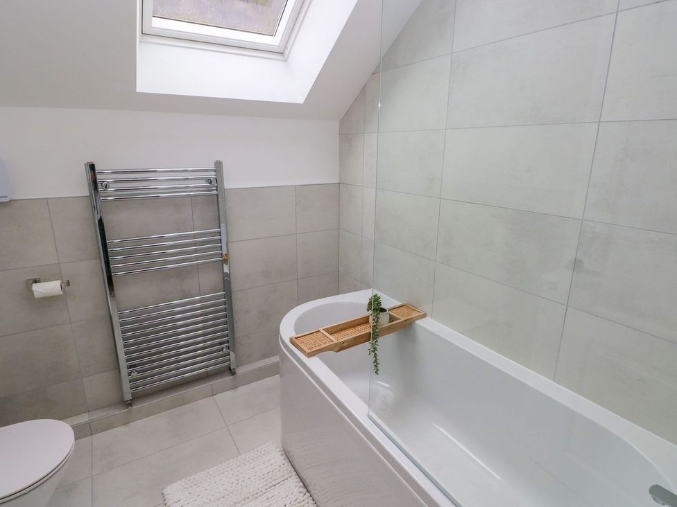 A bathroom with a bathtub and towel rail at Hafan Y Gof in Newcastle Emlyn