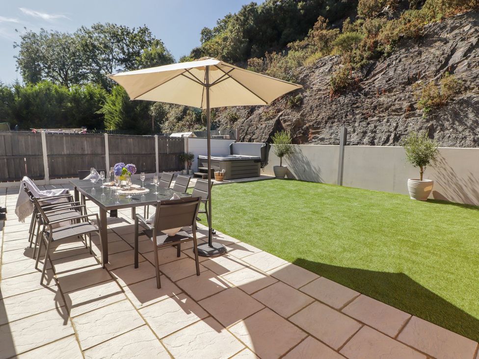 A garden with a dining table and chairs under an umbrella at Hafan Y Gof Newcastle Emlyn