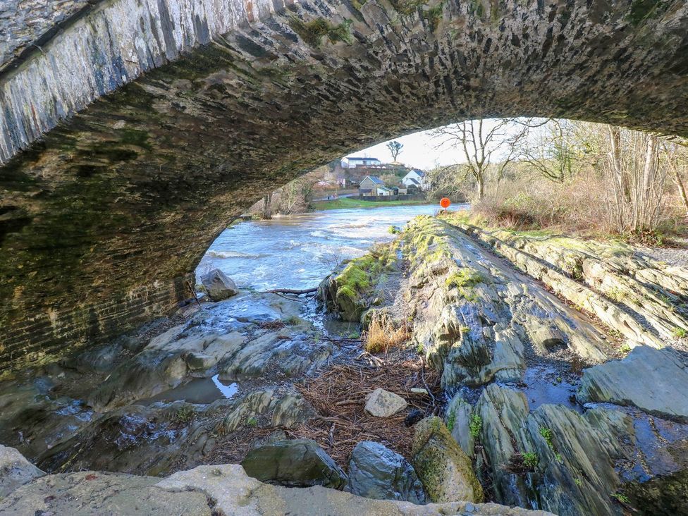 A bridge over a stream with rocks and vegetation at Hafan Y Gof Newcastle Emlyn