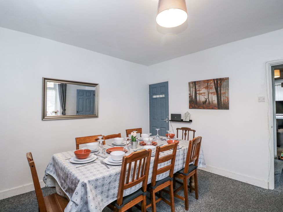 A dining table with chairs and a mirror at Maindy Lodge