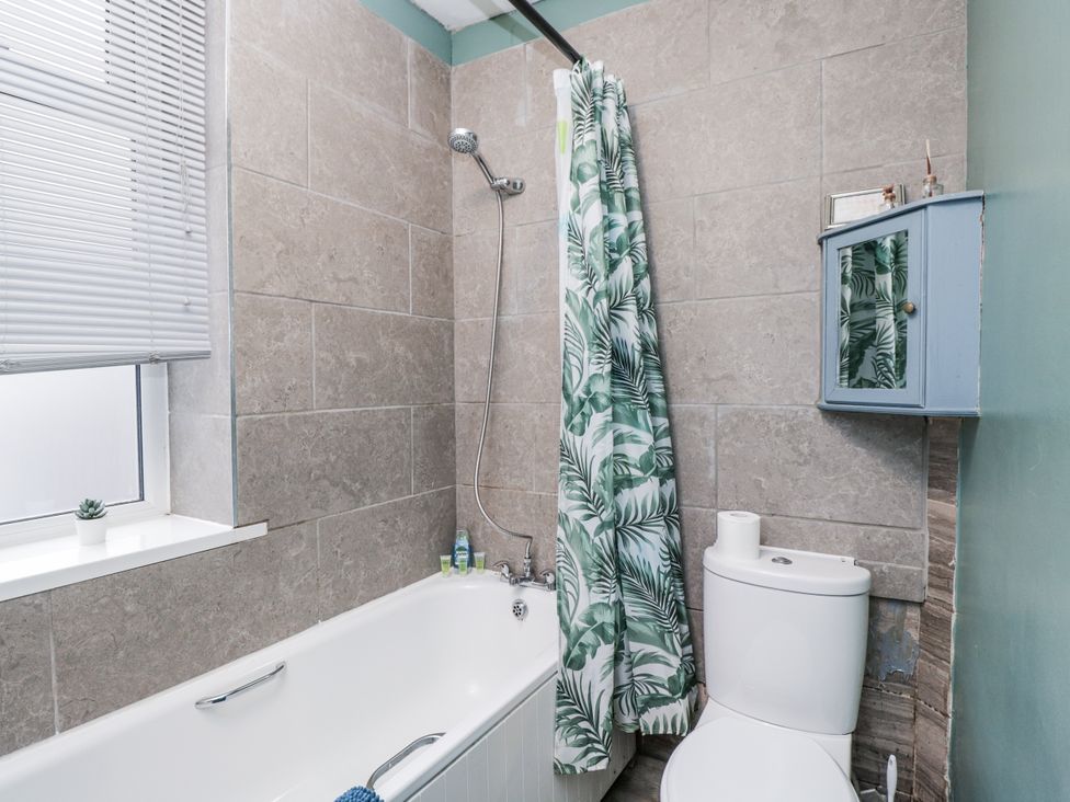 A bathroom with a bathtub, shower, toilet, and a window at Maindy Lodge