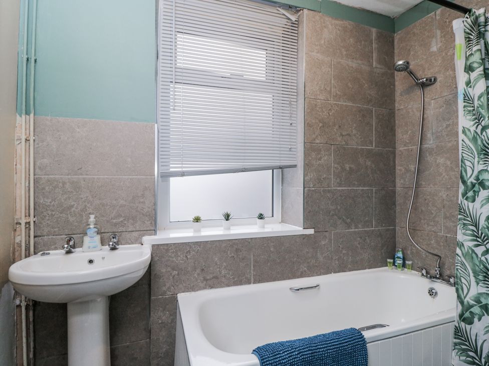 A bathroom with a bathtub and washbasin at Maindy Lodge