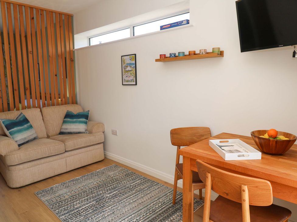 A living room with a sofa, dining table, and television at Carn Brea in Redruth