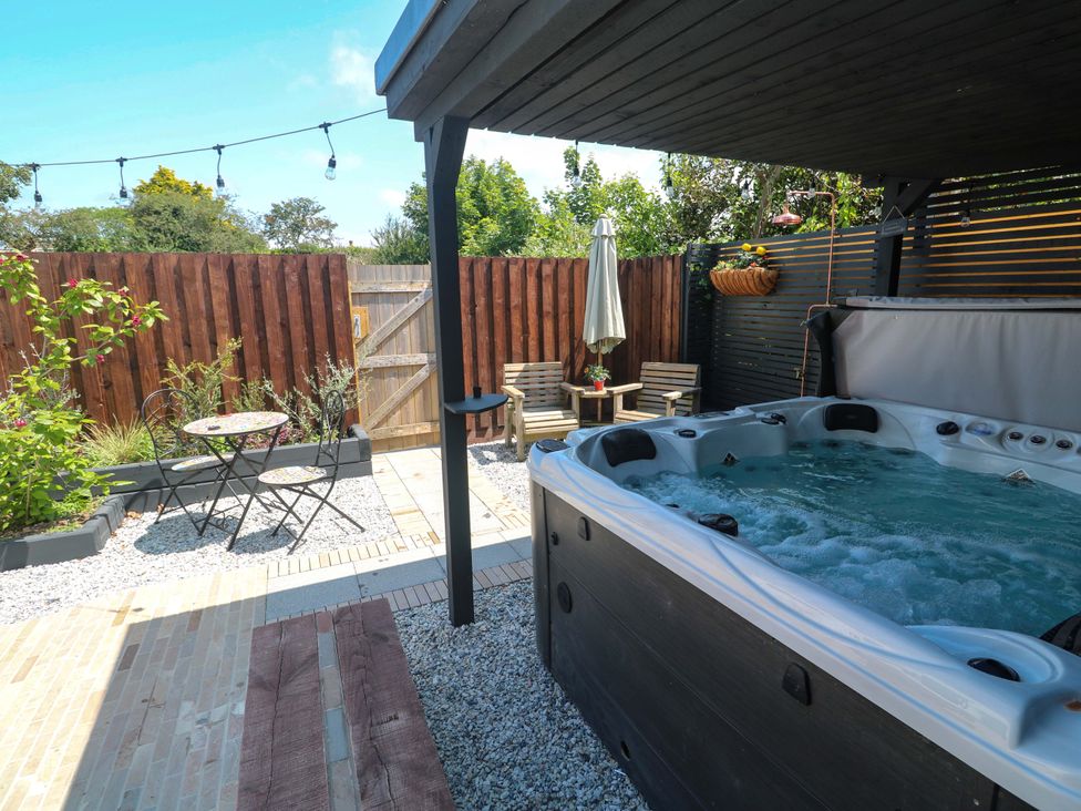 A garden with a hot tub, table, and chairs at Carn Brea in Redruth