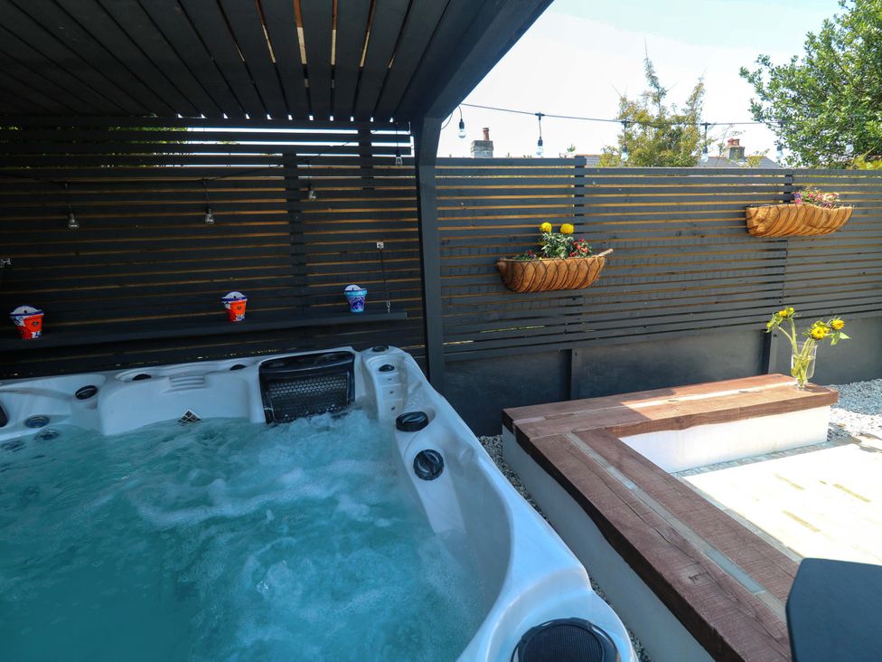 A hot tub with a wooden bench and flower pots at Carn Brea in Redruth