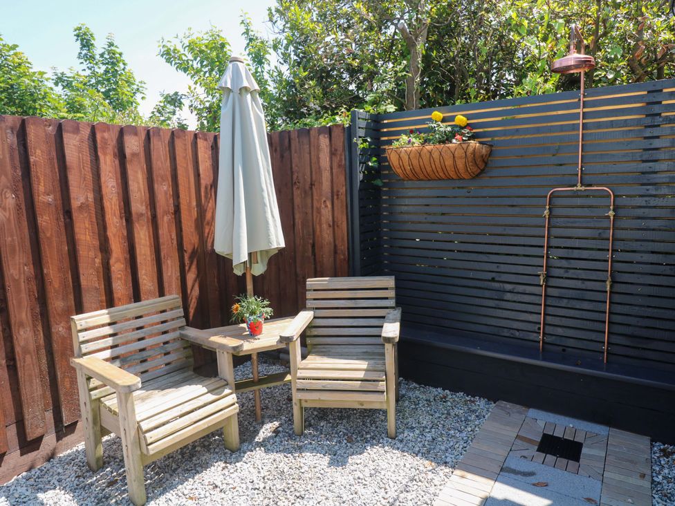 A garden with wooden chairs and a table at Carn Brea in Redruth