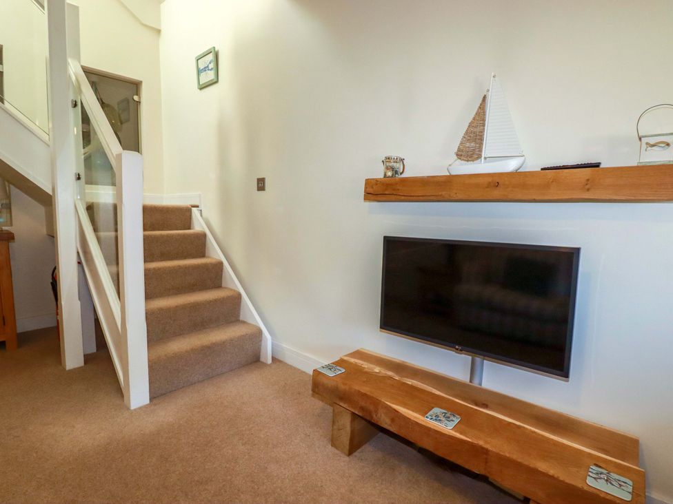 A hallway with stairs and a television on a wooden bench at 3 The Old Cornstore