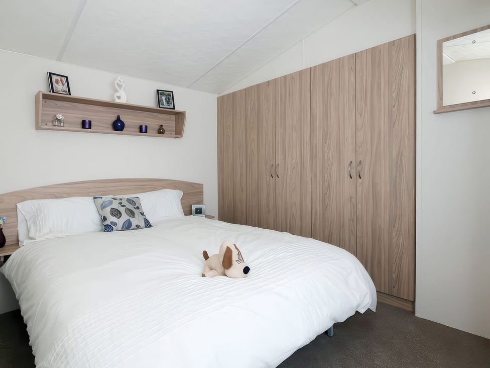 A bedroom with a bed, wardrobe, and shelf at Nature's Nook - Billing Aquadrome