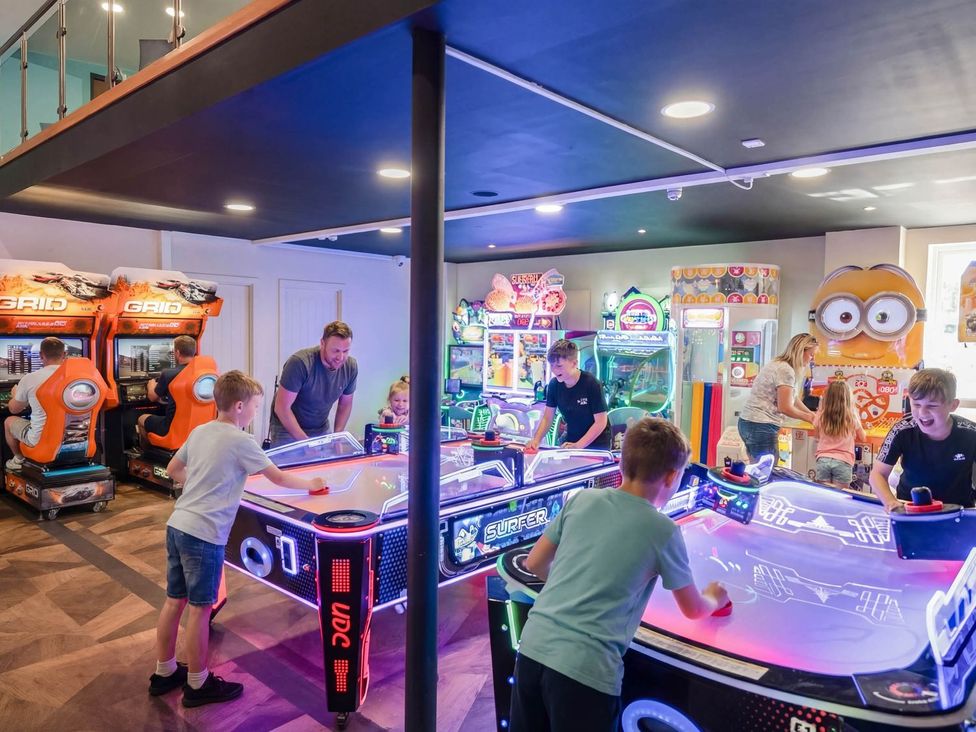 A game room with arcade machines and children playing at Nature's Nook - Billing Aquadrome