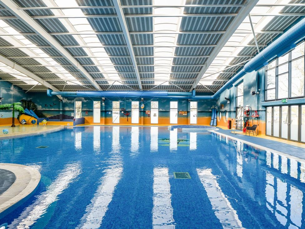 An indoor pool with a water slide and lifeguard chair at Nature's Nook - Billing Aquadrome