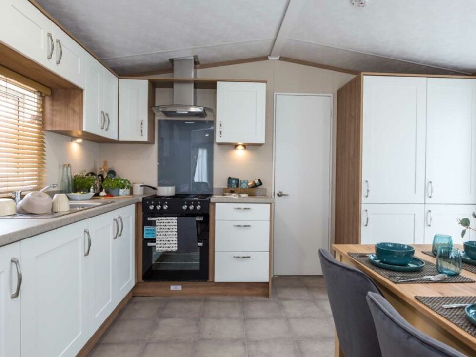 A kitchen with oven and dining table at Aquadrome Abode 3bed - Billing Aquadrome