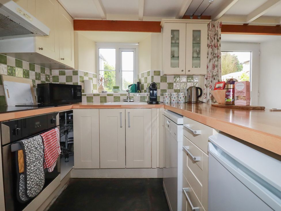 A kitchen with various appliances and a window at Trevean Bude