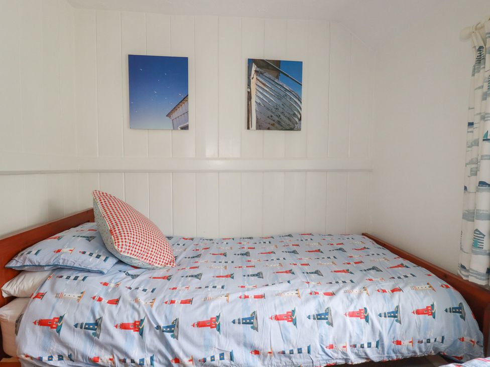A bedroom with a bed, patterned bedding, and wall art at Trevean in Bude